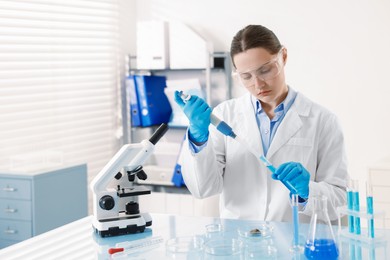 Photo of Scientist working with sample in Petri dish at table in laboratory