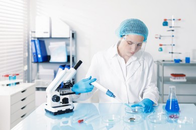 Photo of Scientist working with sample in Petri dish at table in laboratory