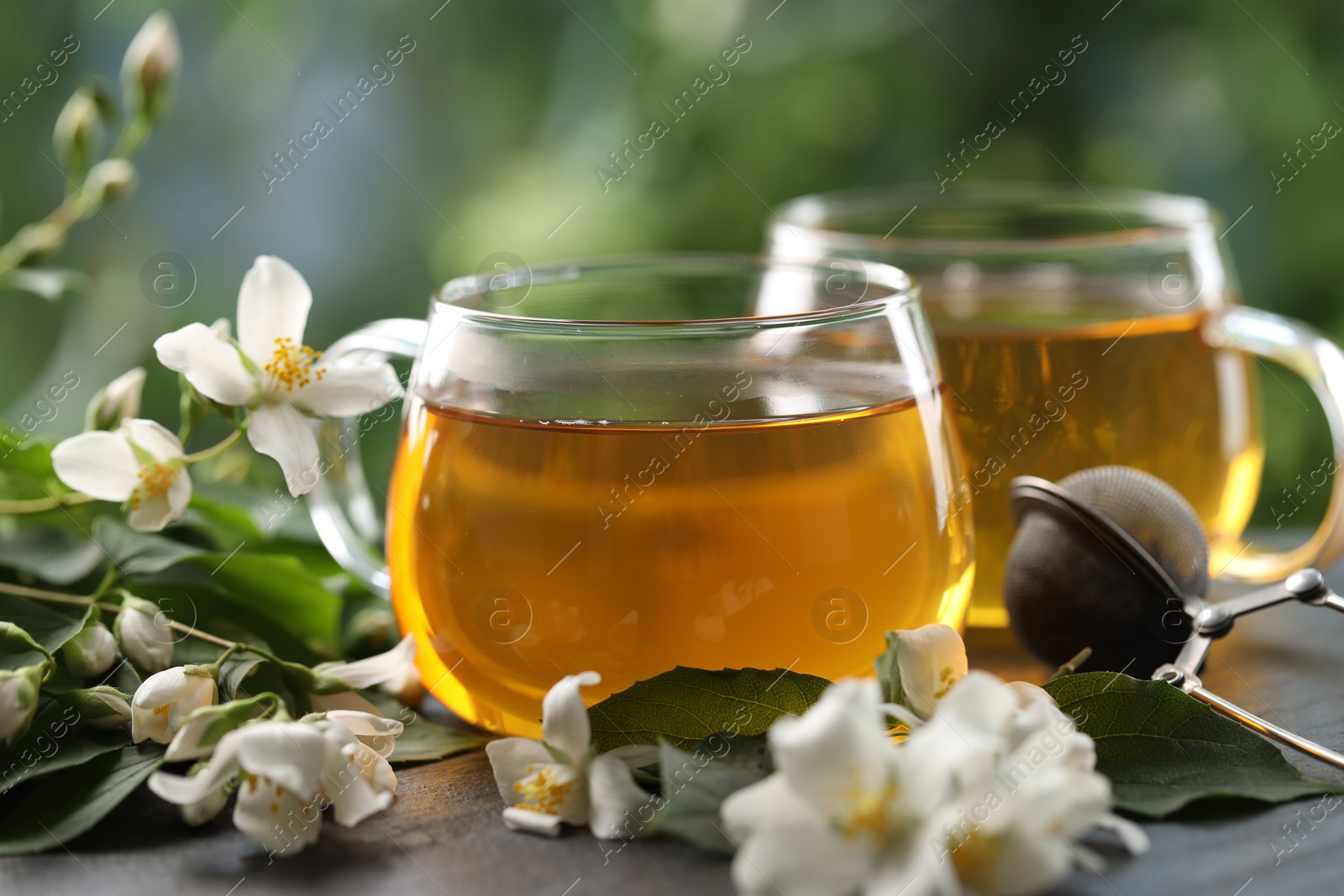 Tasty jasmine tea in cups, dry leaves and flowers on black table, closeup Photo of Tasty jasmine tea in cups, dry leaves and flowers on black table, closeup