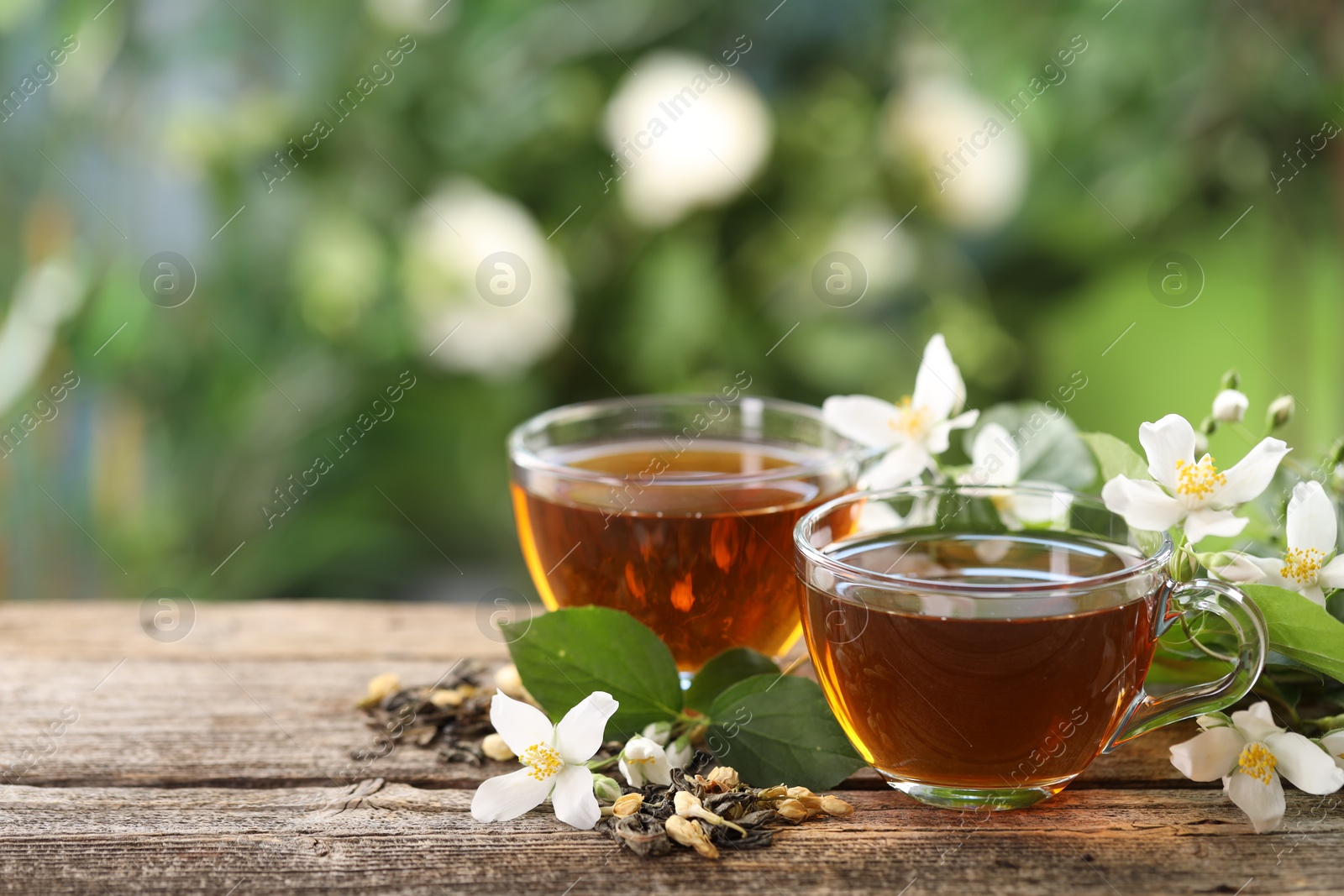 Tasty jasmine tea in cups, dry leaves and flowers on wooden table, closeup. Space for text Photo of Tasty jasmine tea in cups, dry leaves and flowers on wooden table, closeup. Space for text