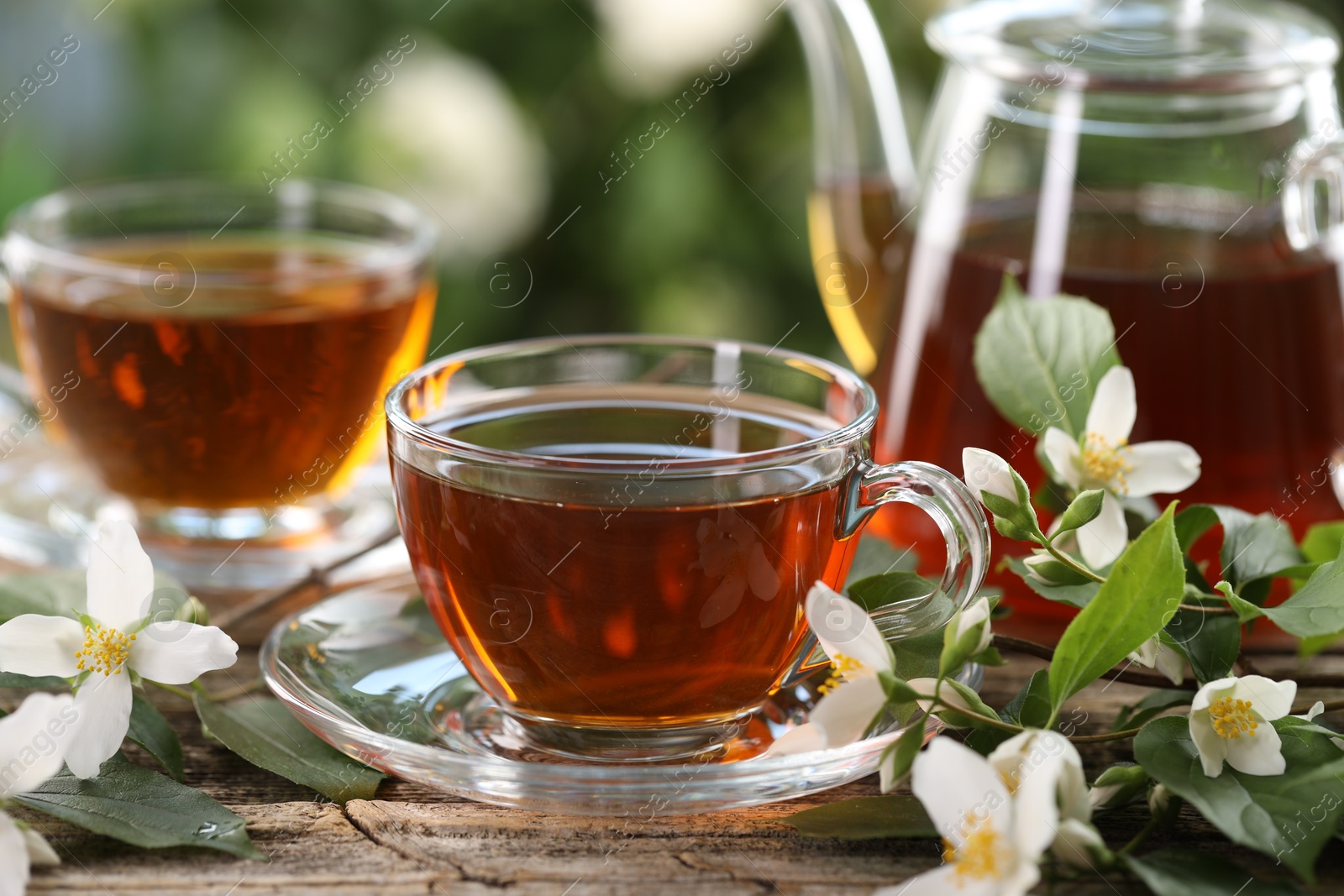 Tasty jasmine tea in cups, teapot and flowers on wooden table, closeup Photo of Tasty jasmine tea in cups, teapot and flowers on wooden table, closeup