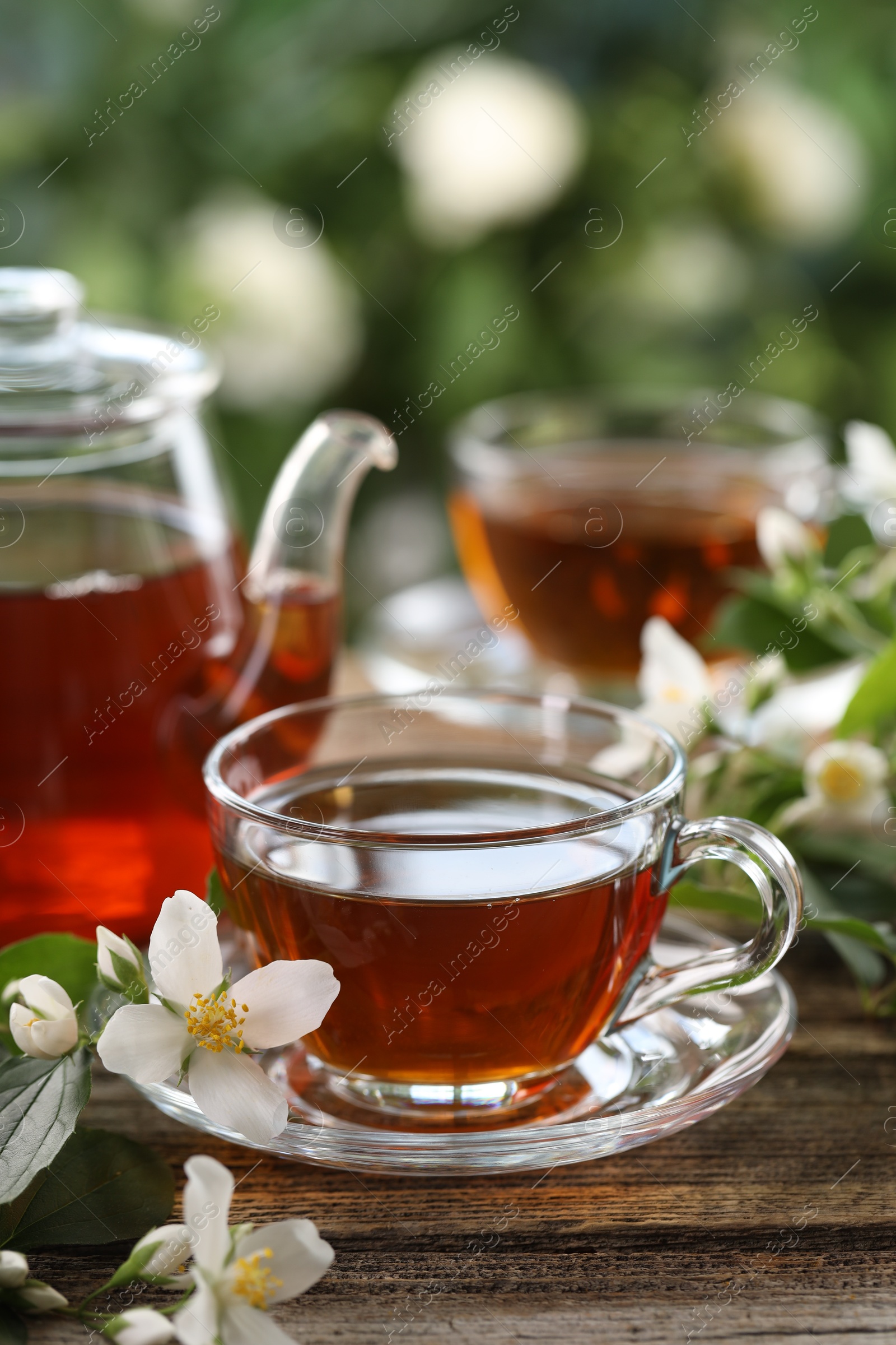 Tasty jasmine tea in cups, teapot and flowers on wooden table, closeup Photo of Tasty jasmine tea in cups, teapot and flowers on wooden table, closeup