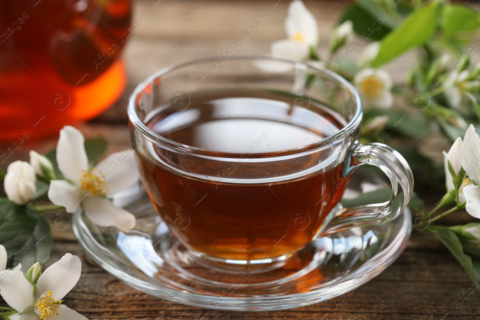 Tasty jasmine tea in cup and flowers on wooden table, closeup Photo of Tasty jasmine tea in cup and flowers on wooden table, closeup