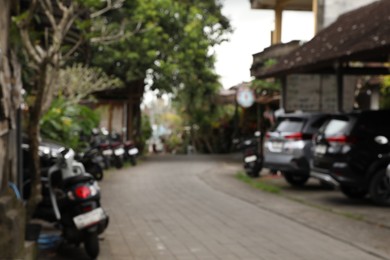 Photo of Blurred view of cars and scooters parked near buildings