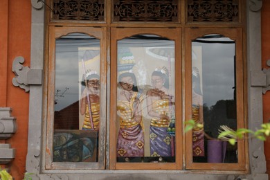 Photo of Bali, Indonesia - May 31, 2025: Drawing of women in traditional clothes, view through window
