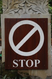 Photo of Wooden board with stop sign on post outdoors