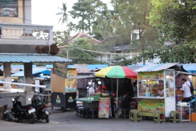 Photo of Blurred view of people, buildings and scooters on city street