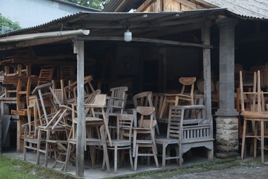 Photo of Many old wooden chairs and tables in storage