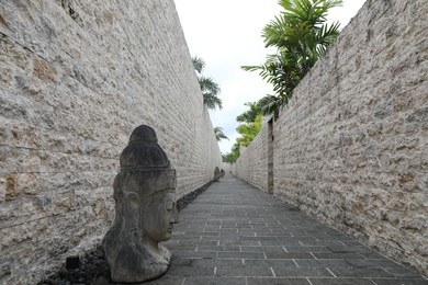 Photo of Bali, Indonesia - June 7, 2025: Beautiful paved pathway, walls and Buddha head statues outdoors