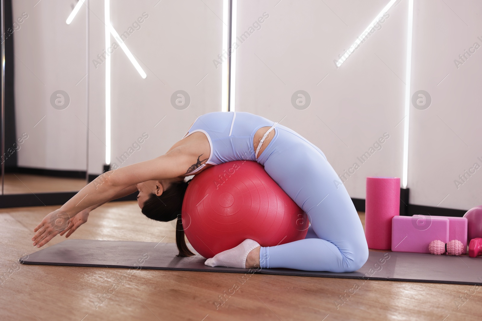 Woman exercising with fitness ball on mat in studio Photo of Woman exercising with fitness ball on mat in studio
