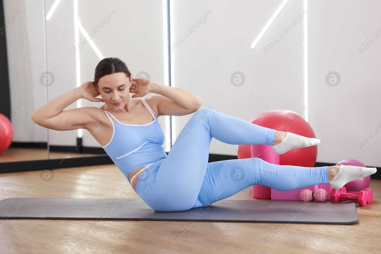 Woman exercising on mat in fitness studio Photo of Woman exercising on mat in fitness studio