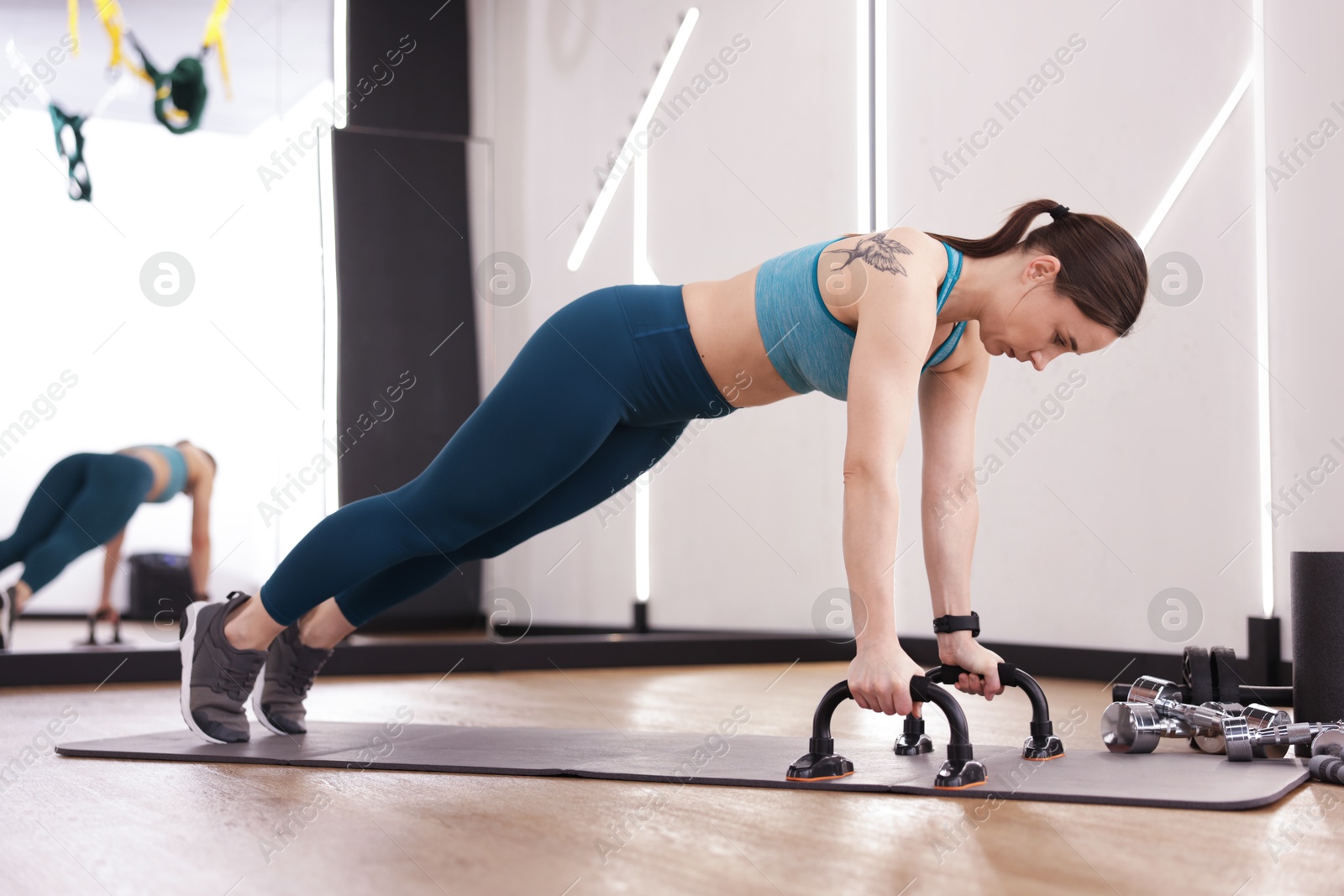 Woman exercising with push up bars in fitness studio Photo of Woman exercising with push up bars in fitness studio