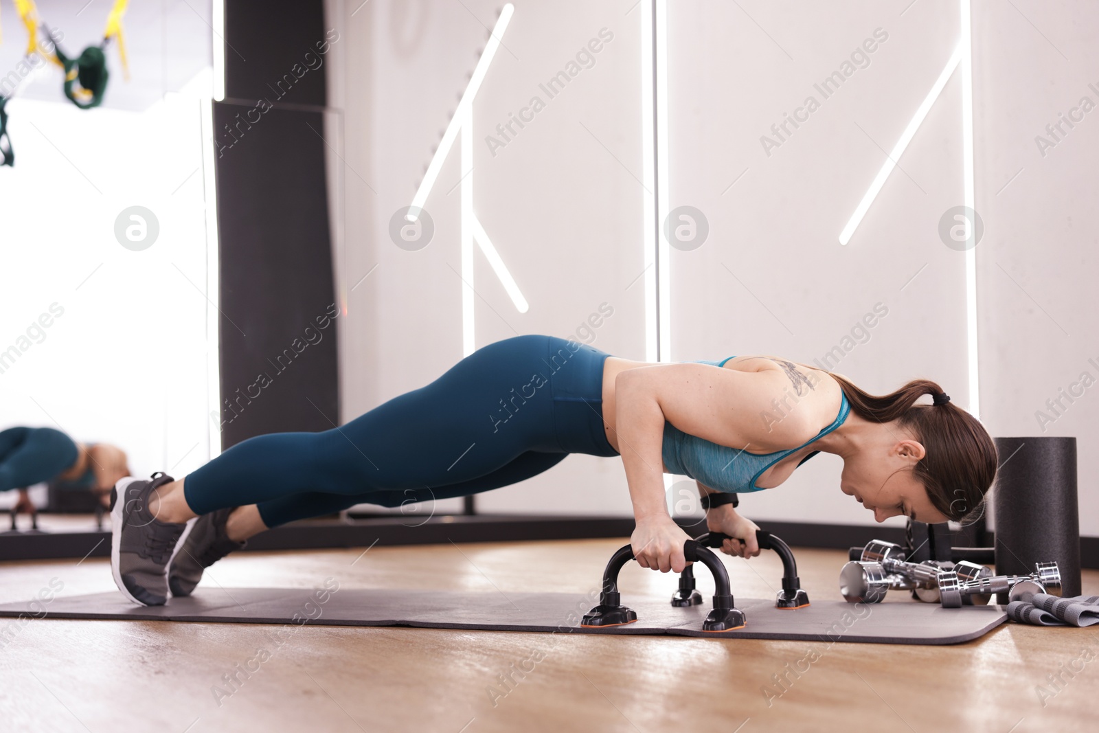 Woman exercising with push up bars in fitness studio Photo of Woman exercising with push up bars in fitness studio