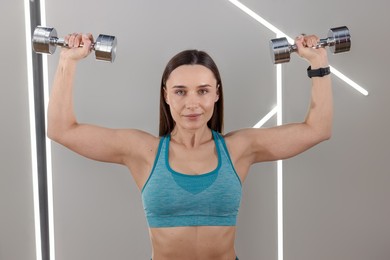 Photo of Woman exercising with dumbbells in fitness studio