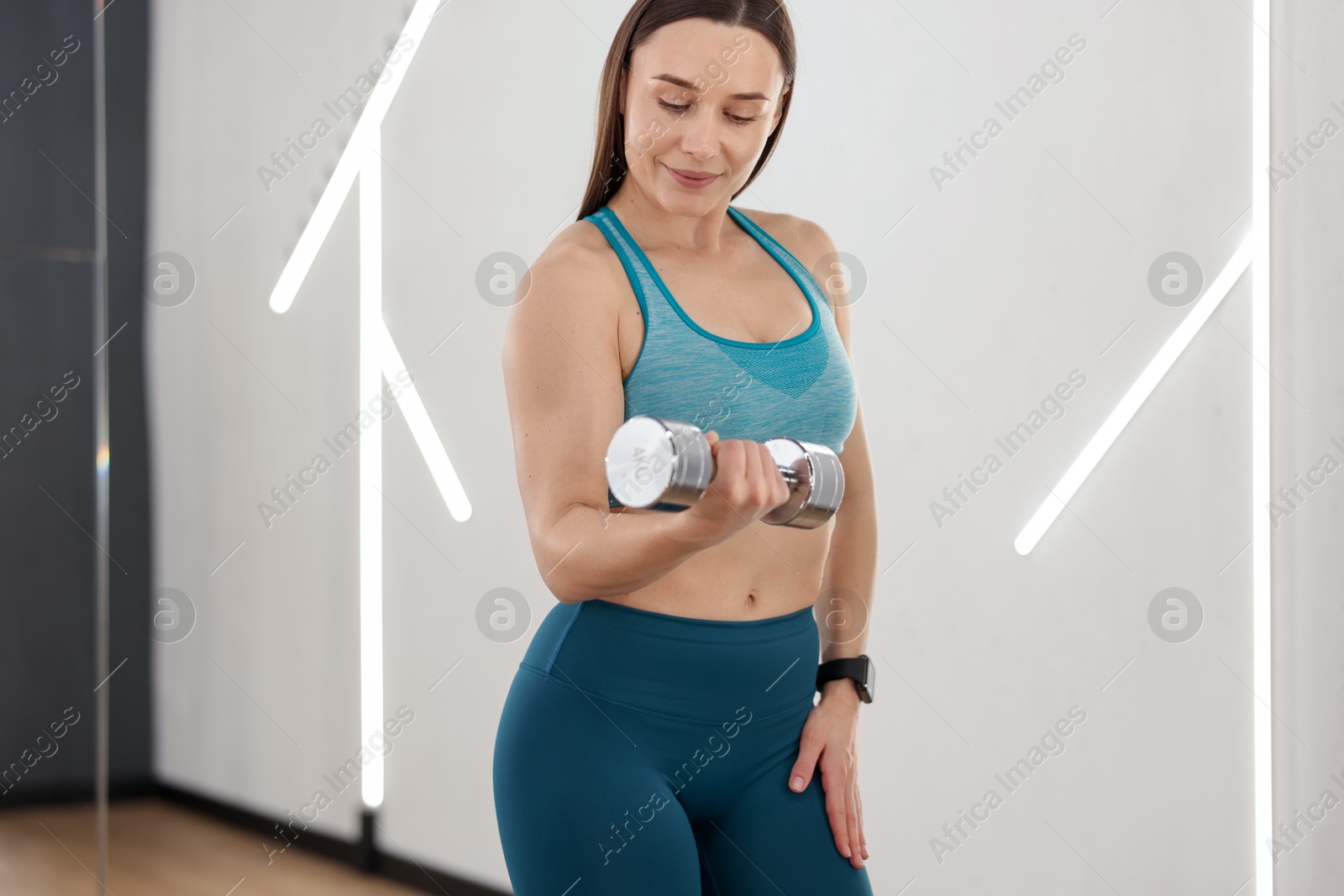 Woman exercising with dumbbell in fitness studio Photo of Woman exercising with dumbbell in fitness studio