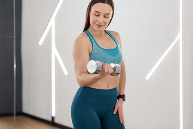 Photo of Woman exercising with dumbbell in fitness studio