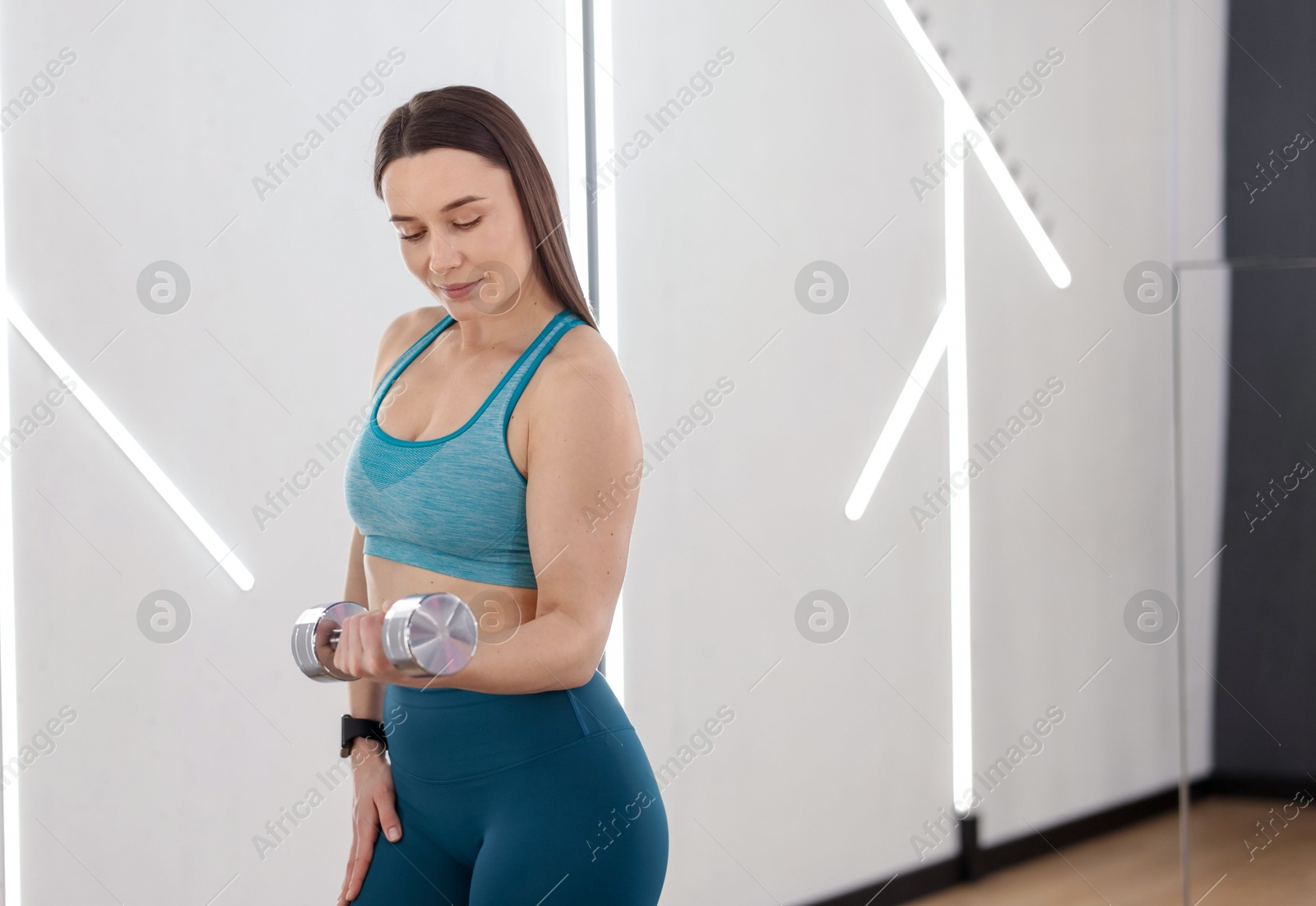 Woman exercising with dumbbell in fitness studio, space for text Photo of Woman exercising with dumbbell in fitness studio, space for text