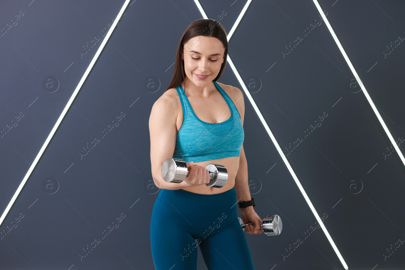 Woman exercising with dumbbells in fitness studio Photo of Woman exercising with dumbbells in fitness studio