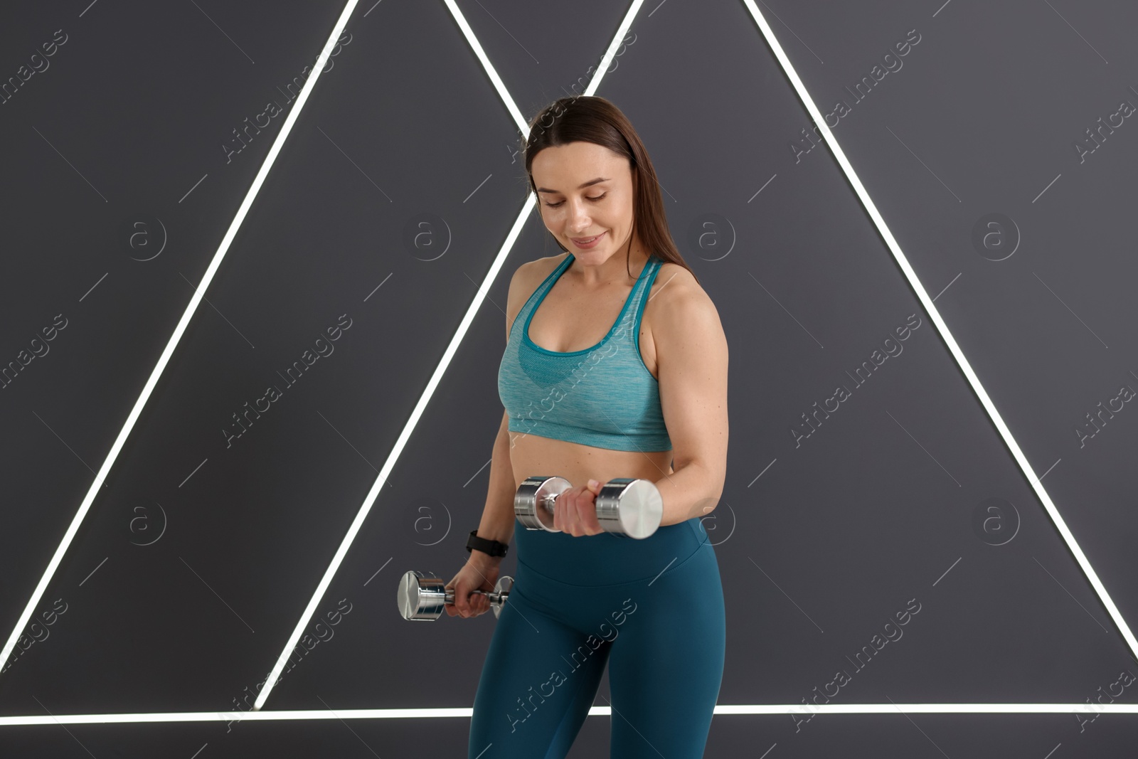 Woman exercising with dumbbells in fitness studio Photo of Woman exercising with dumbbells in fitness studio