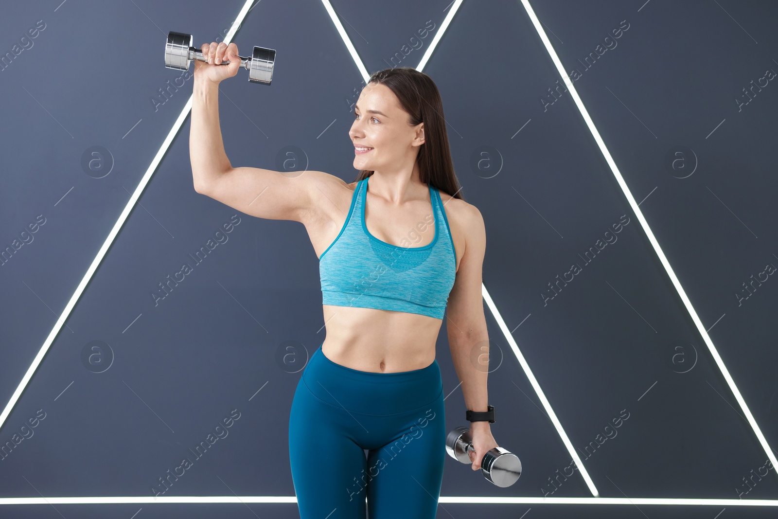 Woman exercising with dumbbells in fitness studio Photo of Woman exercising with dumbbells in fitness studio