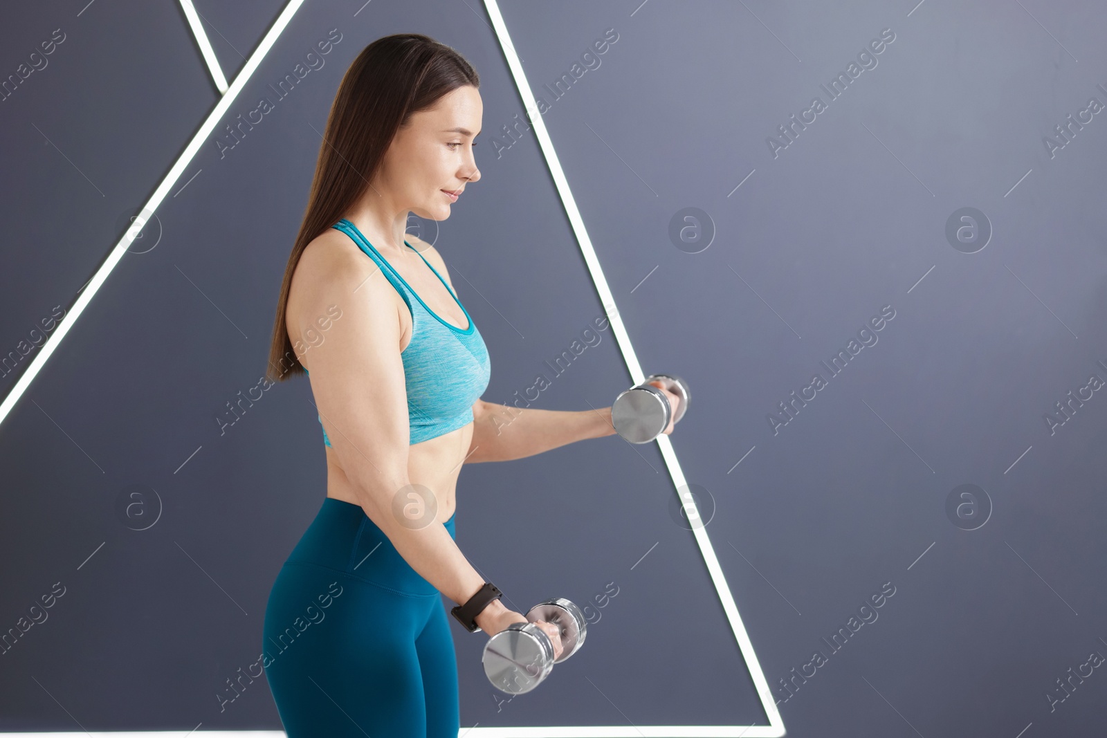 Woman exercising with dumbbells in fitness studio, space for text Photo of Woman exercising with dumbbells in fitness studio, space for text