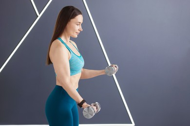 Photo of Woman exercising with dumbbells in fitness studio, space for text