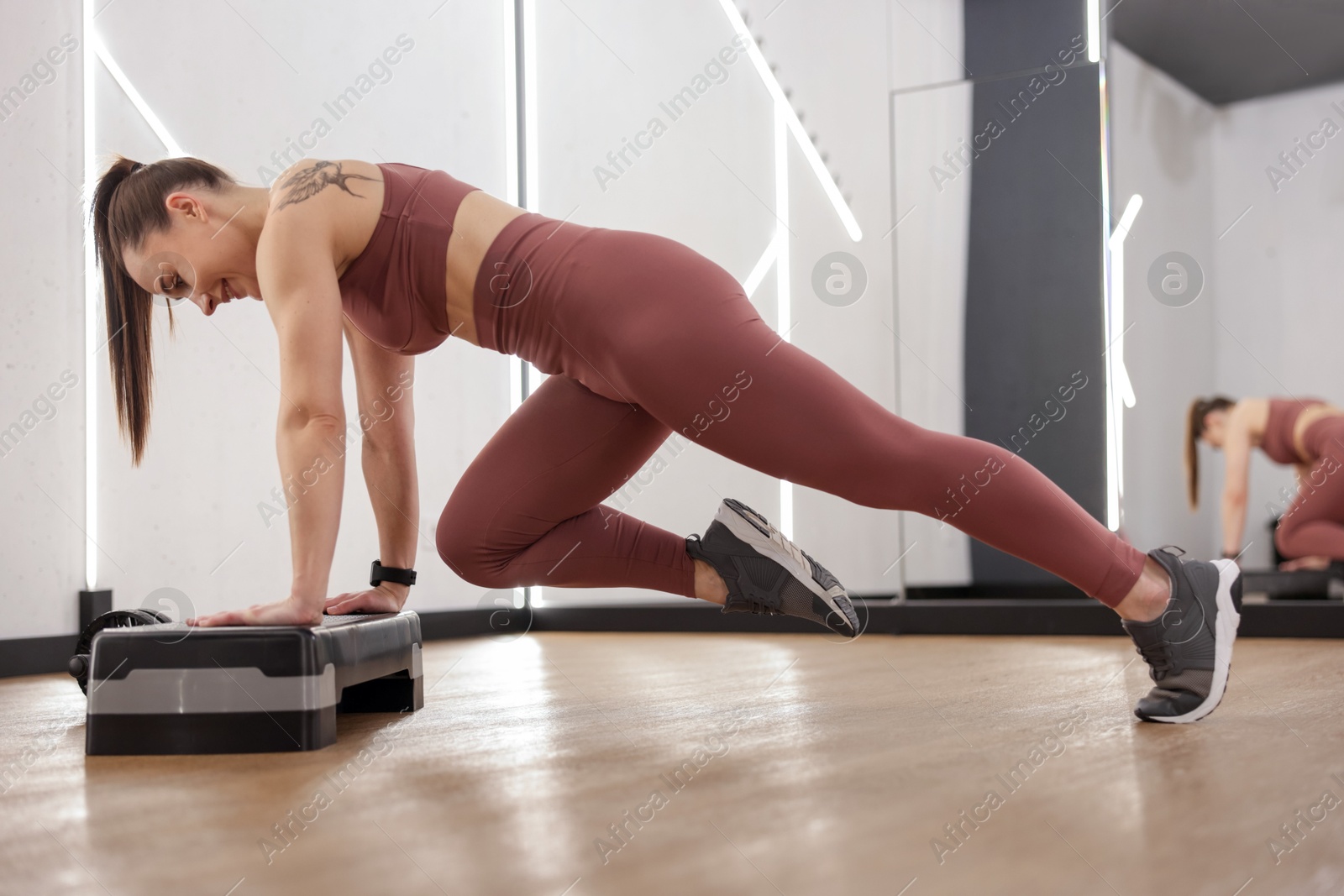 Woman exercising with step platform in fitness studio Photo of Woman exercising with step platform in fitness studio