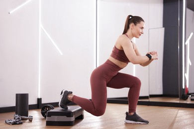 Photo of Woman exercising with step platform in fitness studio