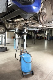 Photo of Dirty old motor oil dripping from car engine into container in workshop