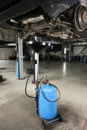 Photo of Dirty old motor oil dripping from car engine into container in workshop