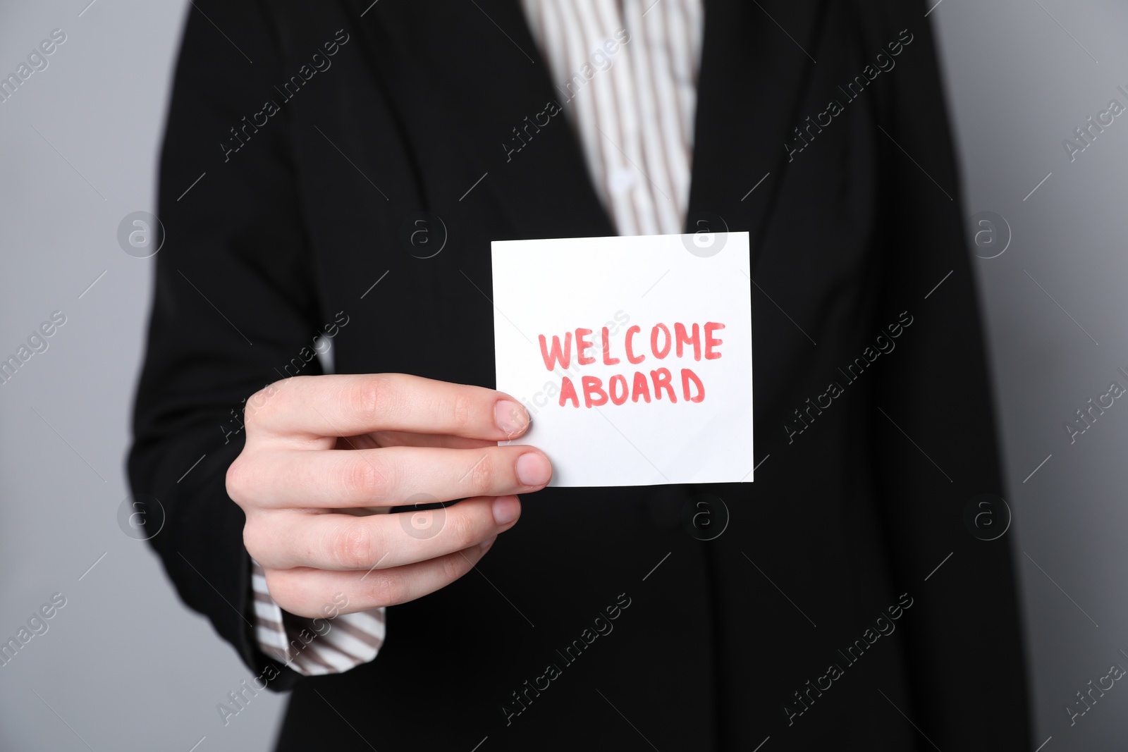 Human resources manager holding sticky note with words Welcome Aboard on grey background, closeup Photo of Human resources manager holding sticky note with words Welcome Aboard on grey background, closeup