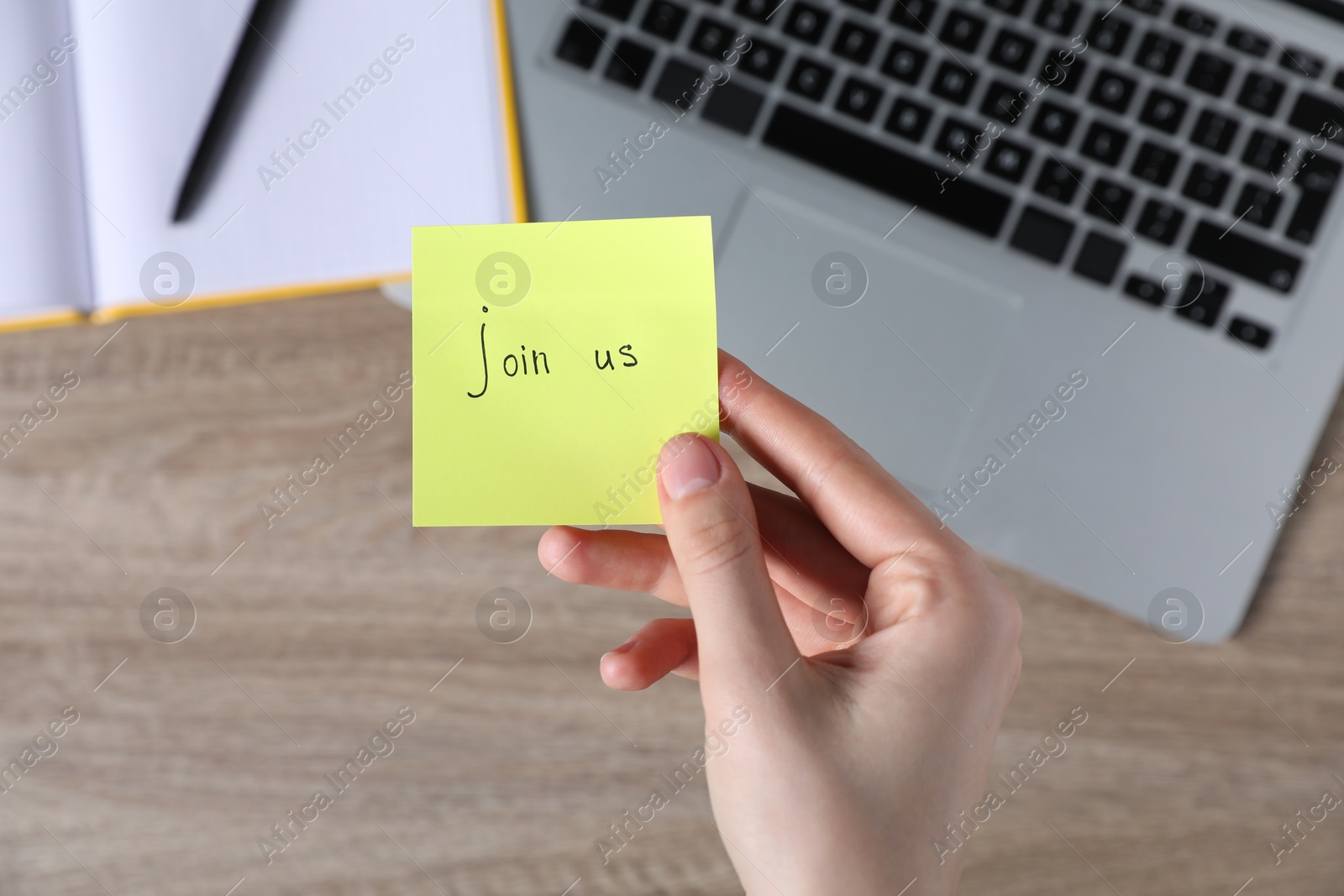 Woman holding paper note with words Join Us at wooden table, top view Photo of Woman holding paper note with words Join Us at wooden table, top view