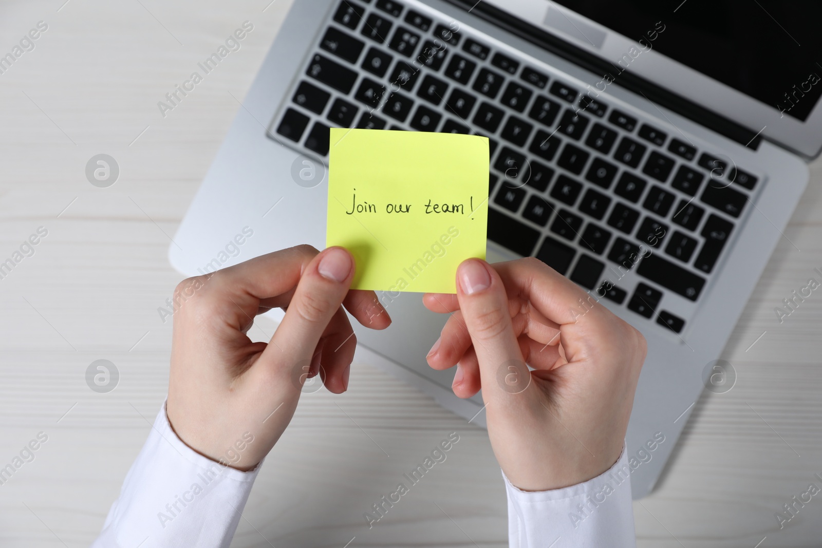Woman holding paper note with words Join Our Team at light wooden table, top view Photo of Woman holding paper note with words Join Our Team at light wooden table, top view
