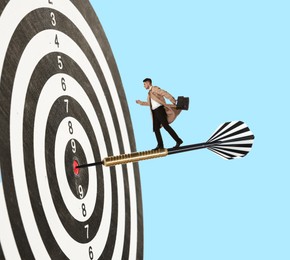 Image of Targeting, goal achievement. Art collage with businessman walking on dart sticking in center of dartboard against light blue background