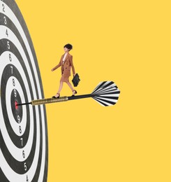 Image of Concepts of targeting, decision and goal achievement. Businesswoman walking on dart sticking in center of dartboard against yellow background