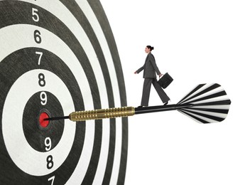 Image of Goal achievement, business success and targeting. Businesswoman walking on dart sticking in center of dartboard against white background
