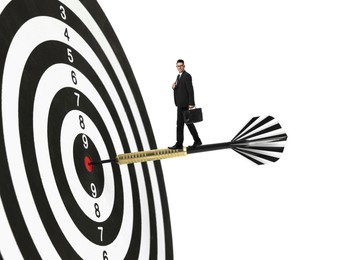 Image of Targeting, goal achievement. Art collage with businessman standing on dart sticking in center of dartboard against white background