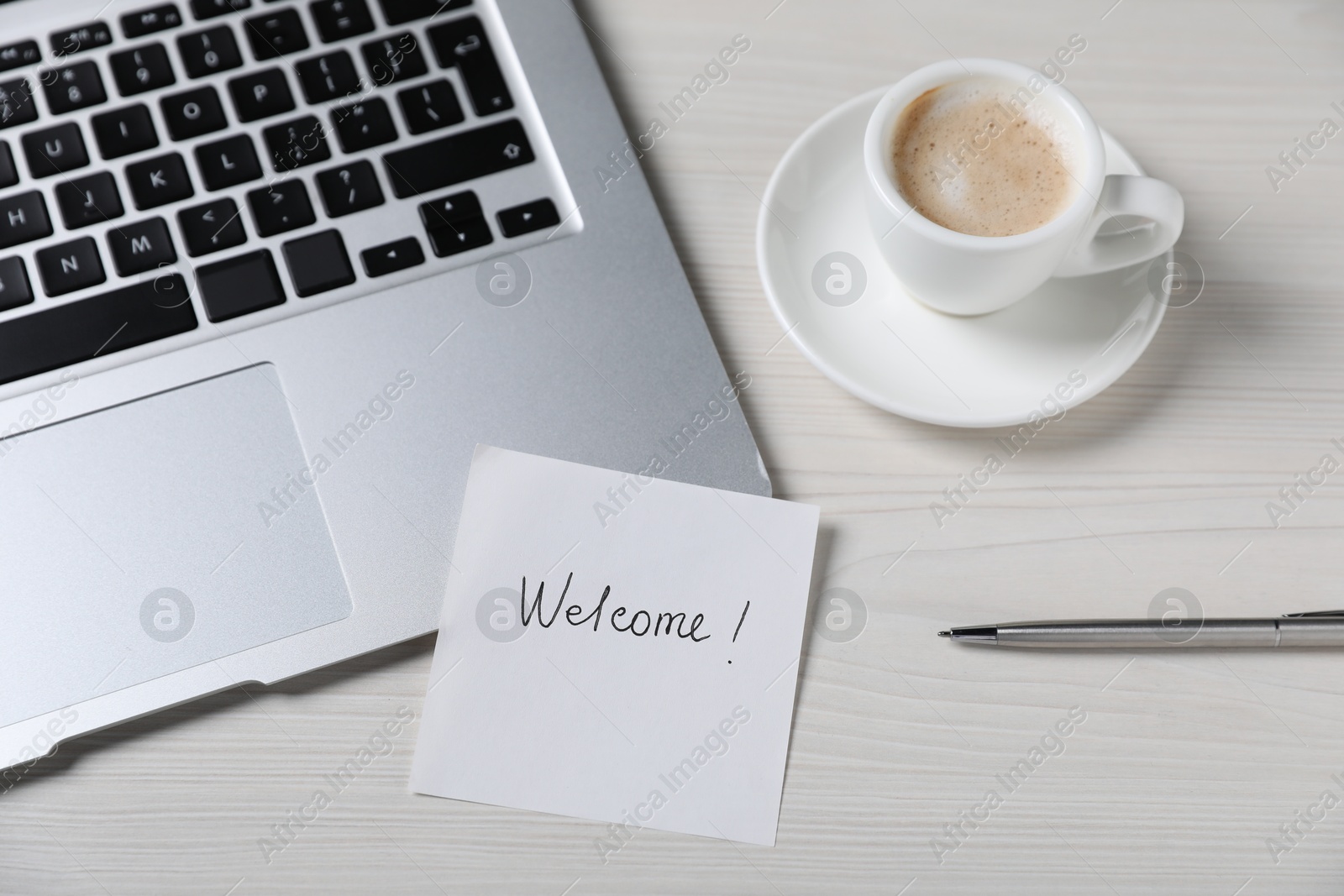 Paper note with word Welcome, laptop, cup of coffee and pen on light wooden table, above view Photo of Paper note with word Welcome, laptop, cup of coffee and pen on light wooden table, above view