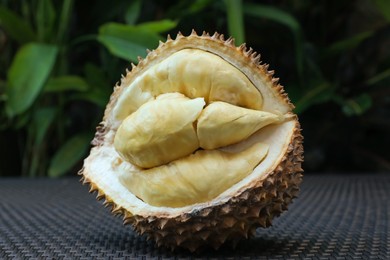 Photo of Fresh ripe durian on wicker table outdoors, closeup