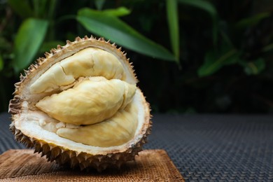 Photo of Fresh ripe durian on wicker table outdoors, space for text