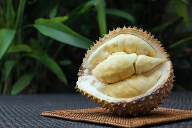 Photo of Fresh ripe durian on wicker table outdoors, space for text
