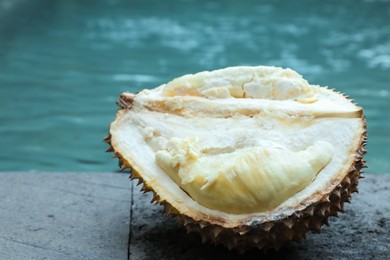 Photo of Fresh ripe durian on stone surface near swimming pool outdoors, closeup. Space for text