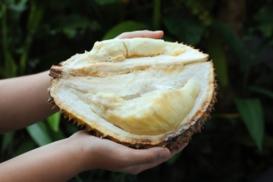 Photo of Woman with fresh ripe durian outdoors, closeup
