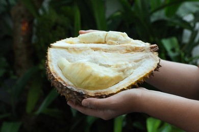 Photo of Woman with fresh ripe durian outdoors, closeup