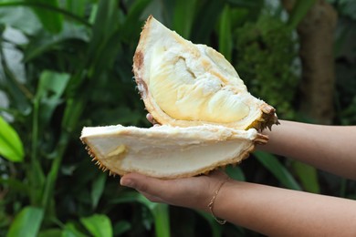Photo of Woman with pieces of fresh ripe durian outdoors, closeup
