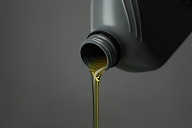 Photo of Pouring motor oil from canister on grey background, closeup. Space for text