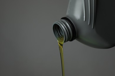 Photo of Pouring motor oil from canister on grey background, closeup. Space for text