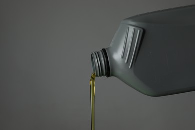 Photo of Pouring motor oil from canister on grey background, closeup. Space for text