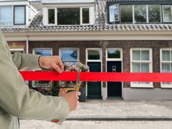 Image of Man cutting red ribbon at opening ceremony of housing estate, closeup