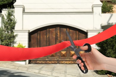 Image of Woman cutting red ribbon at opening ceremony of house, closeup